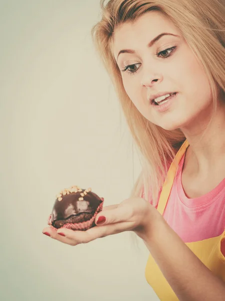 Жінка тримає шоколадний кекс збирається вкусити — стокове фото