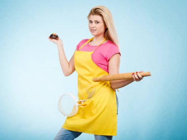 Tutan cupcake, oklava, kevgir önlük giyen kadın