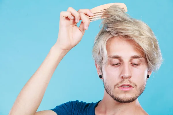Мужчина со стильной прической расчесывает волосы — стоковое фото