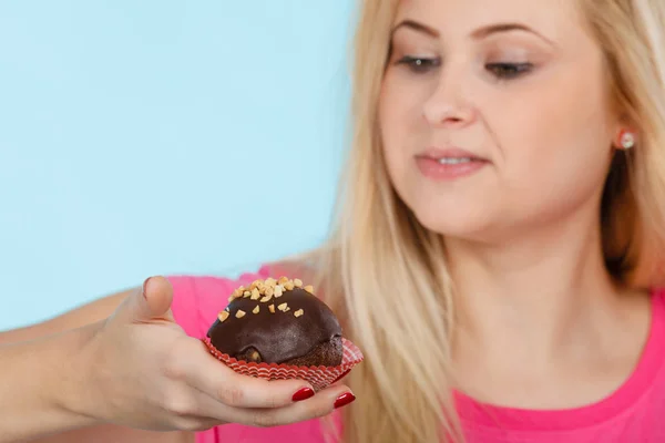 Woman holding chocolate cupcake about to bite