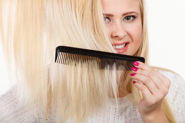 Mulher loira escovando seu cabelo longo com pente — Fotografia de Stock