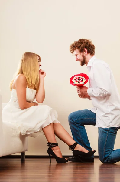 Mann überreicht Frau Bonbonstrauß Blumen. Glückliches Paar — Stockfoto