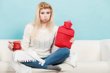 Sıcak su şişesi ve çay Kupası tutan kadın