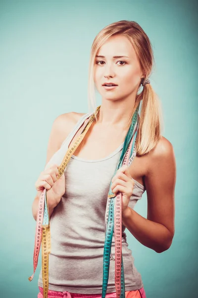 Fit girl with many colorful measure tapes on blue — Stock Photo, Image