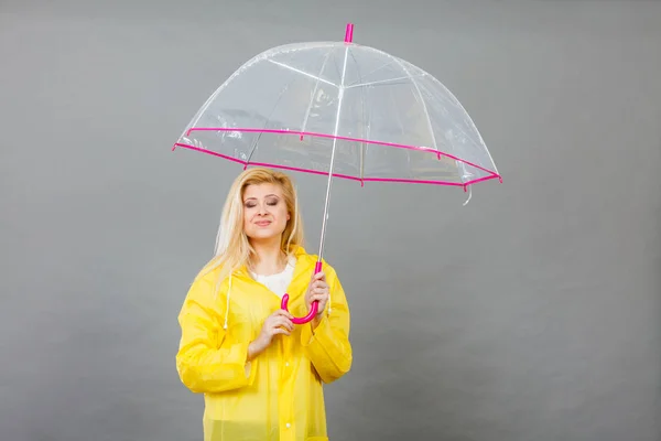 Happy woman wearing raincoat holding transparent umbrella — Stock Photo, Image