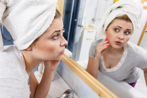 Bir kadın aynadaki yansımasına bakıyor.