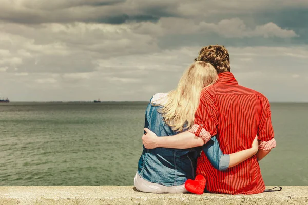 Coppia seduta abbracciata sulla riva del mare — Foto Stock