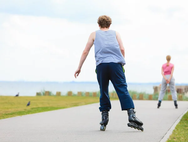 Hombre patinando detrás de la mujer en el paseo marítimo —  Fotos de Stock