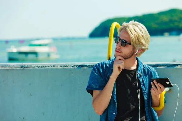 Blonde man in sunglasses listening to music — Stock Photo, Image