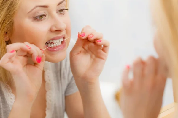 女人清洗她的牙齿，用牙线剔牙 — 图库照片