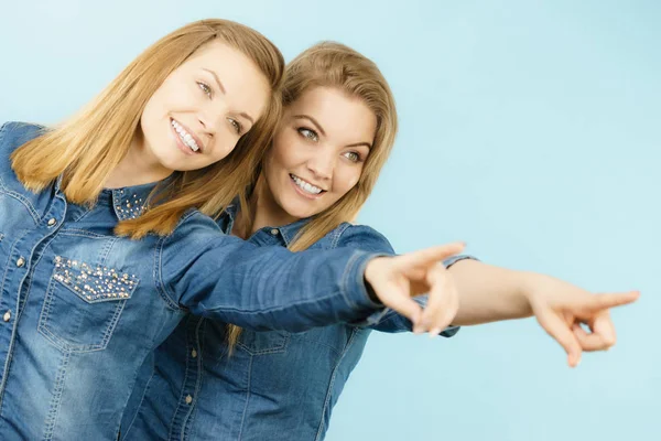 Två glada kvinnor vänner bära jeans outfit poitning — Stockfoto