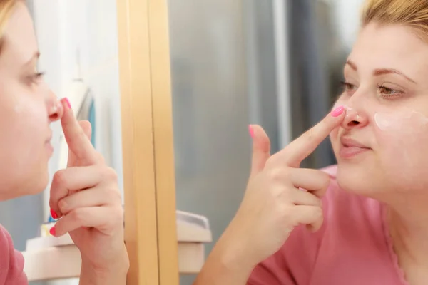 Mujer aplicando crema facial con el dedo — Foto de Stock