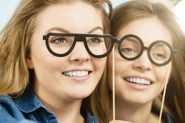 Sahte gözlük sopa üzerinde tutan iki mutlu kadın — Stok fotoğraf