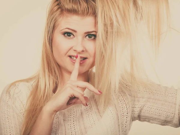 Kvinna som håller hennes blonda hår visar tystnad gest — Stockfoto