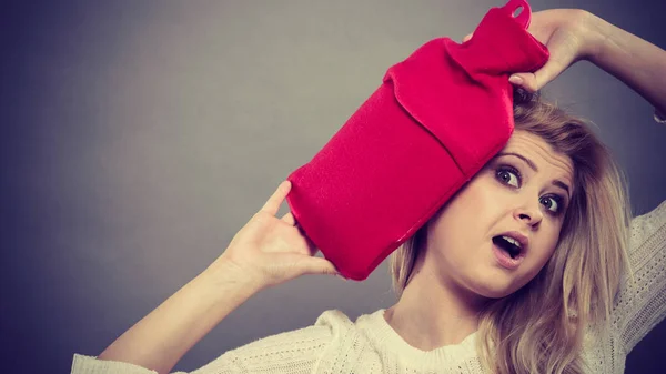 Woman holding red hot water bottle on head — Stock Photo, Image