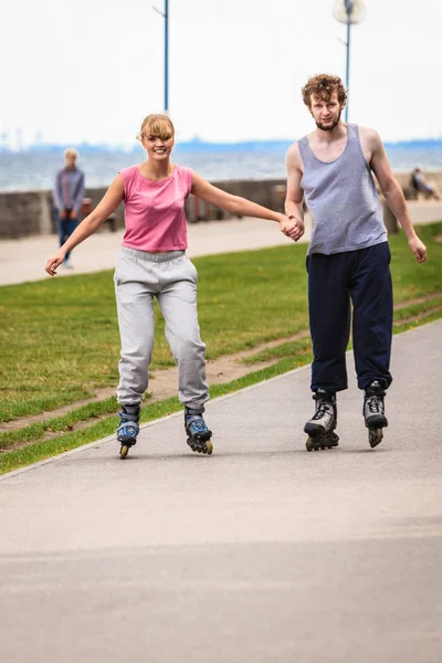 Pareja joven patinando en parque tomados de la mano . — Foto de Stock