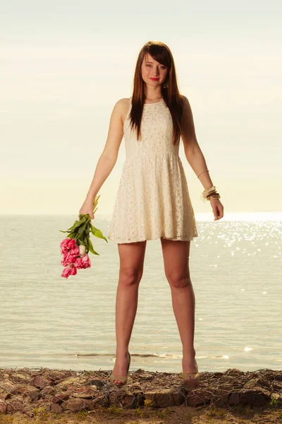 Hermosa mujer sosteniendo ramo de flores en la playa —  Fotos de Stock