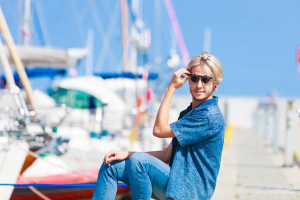 Blonde man sitting near harbor in summer — Stock Photo, Image