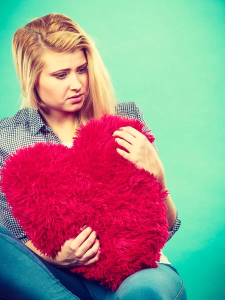 Mujer triste sosteniendo almohada roja en forma de corazón — Foto de Stock
