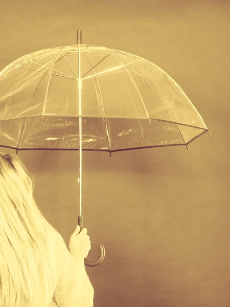 Frau im Regenmantel mit Regenschirm kontrolliert das Wetter — Stockfoto