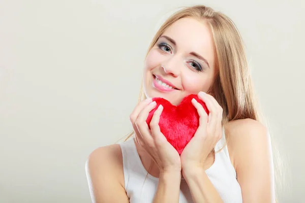 Mujer sonriente sosteniendo el símbolo de amor corazón rojo — Foto de Stock