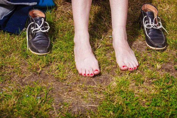 Frauenfüße auf grünem Rasenboden — Stockfoto