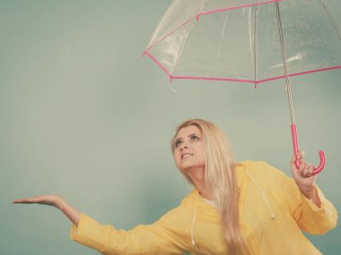 Hava kontrol şemsiye tutan yağmurluk giyen kadın