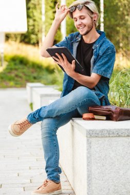 Hipster gülümseyen adam kenarında oturan tablet ile