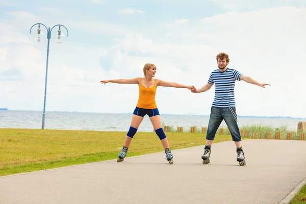 Jovem casal em patins andando ao ar livre — Fotografia de Stock