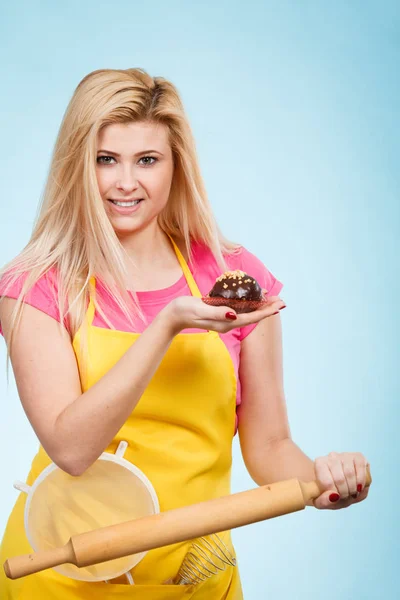 Mulher segurando cupcake, rolo, escorredor vestindo avental — Fotografia de Stock