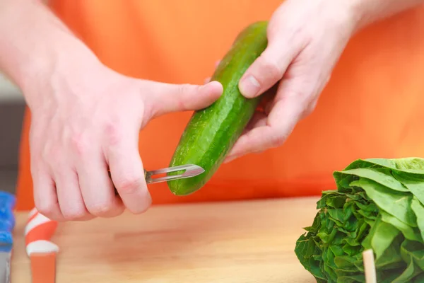 Homem preparando legumes salada descascando pepino — Fotografia de Stock