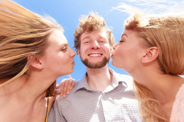 Duas meninas beijando um menino se divertindo ao ar livre — Fotografia de Stock