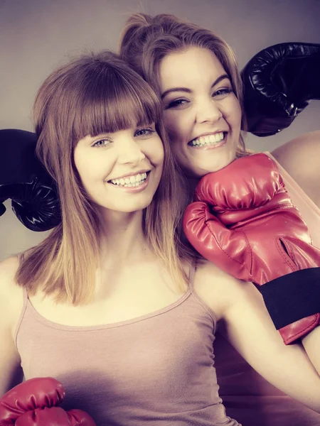 Two women friends wearing boxing gloves