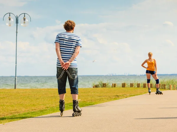 Pareja joven en patines de ruedas montando al aire libre — Foto de Stock