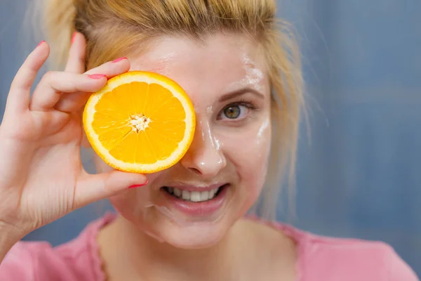 Mulher com máscara de gel no rosto segurando laranja — Fotografia de Stock