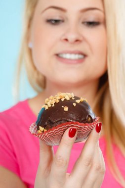 Çikolatalı kek tutan kadın ısırmak üzere.