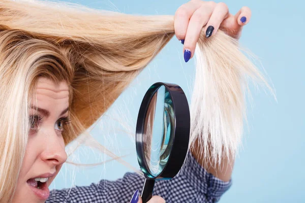 Woman looking at hair through magnifying glass