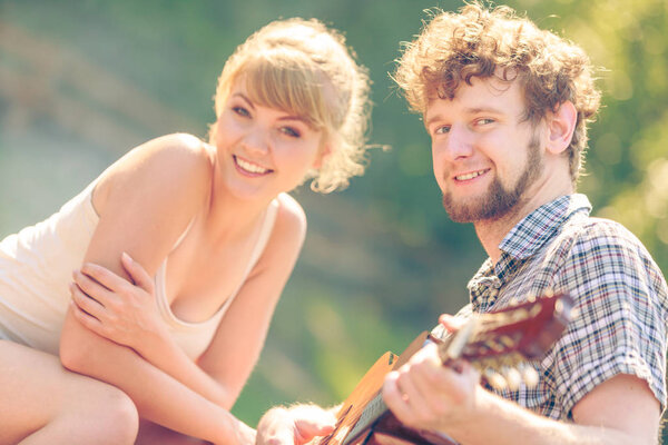 Young couple camping playing guitar outdoor