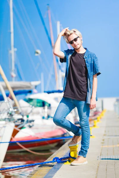 Blonde man standing near harbor in summer