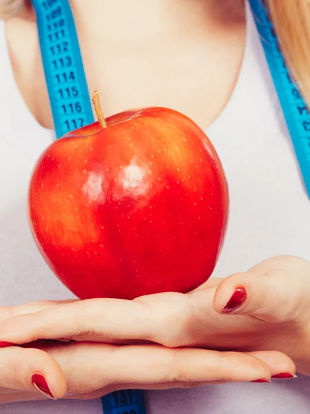 Woman with measuring tape around neck holding apple — Stock Photo, Image