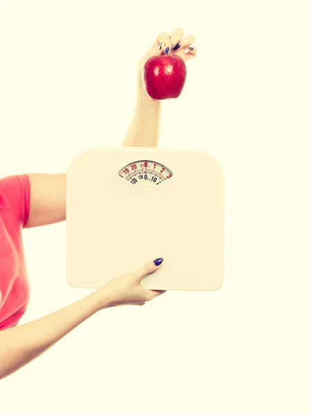 Woman holding apple and weight machine — Stock Photo, Image