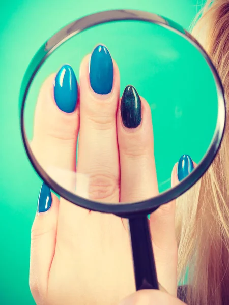Woman looking at nails through magnifying glass Royalty Free Stock Photos