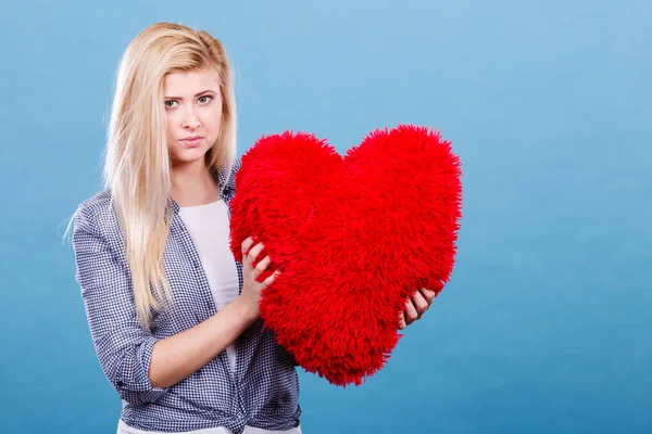 Mujer triste sosteniendo almohada roja en forma de corazón —  Fotos de Stock