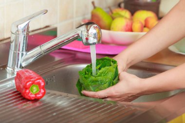 Mutfakta taze sebze yıkayan kadın.