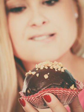 Çikolatalı kek tutan kadın ısırmak üzere.