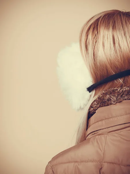 Nainen talvella korvatulpat ja takki takaisin — kuvapankkivalokuva