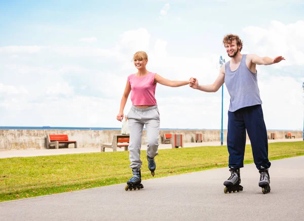 Jovem casal patinagem no parque de mãos dadas . — Fotografia de Stock