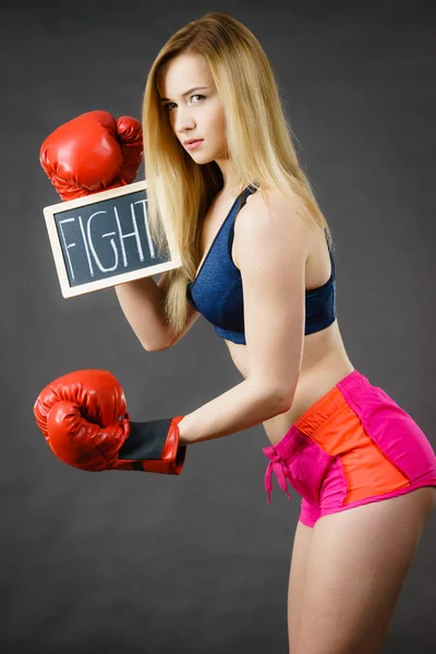 Mulher vestindo luva de boxe segurando sinal de luta — Fotografia de Stock