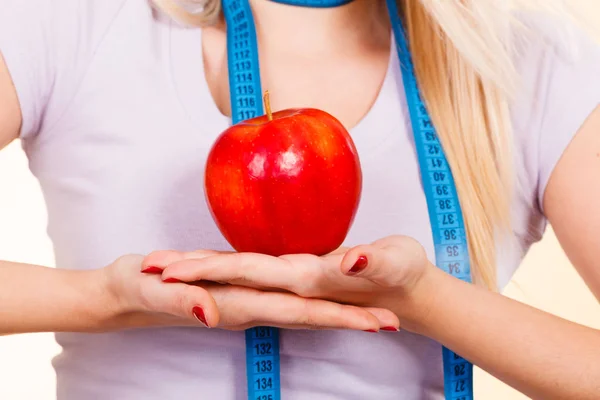 Woman with measuring tape around neck holding apple — Stock Photo, Image