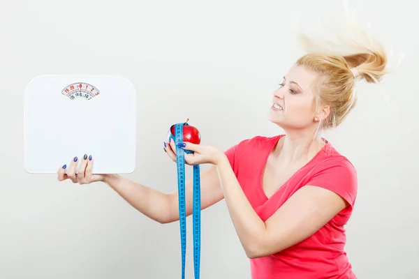 Woman holding apple,measuring tape and weight machine — Stock Photo, Image